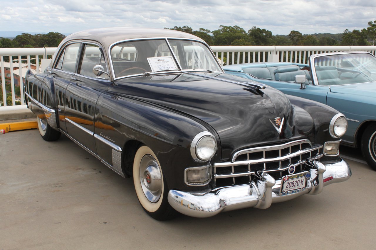 Dark 1948 Cadillac Series 62 sedan with a light roof, viewed from the front three-quarter angle at a car show