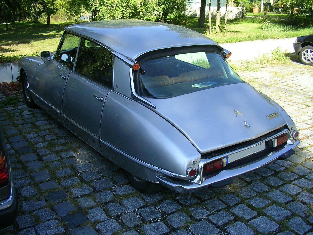 Rear three-quarter view of a silver Citroën DS 21 saloon parked on cobblestones
