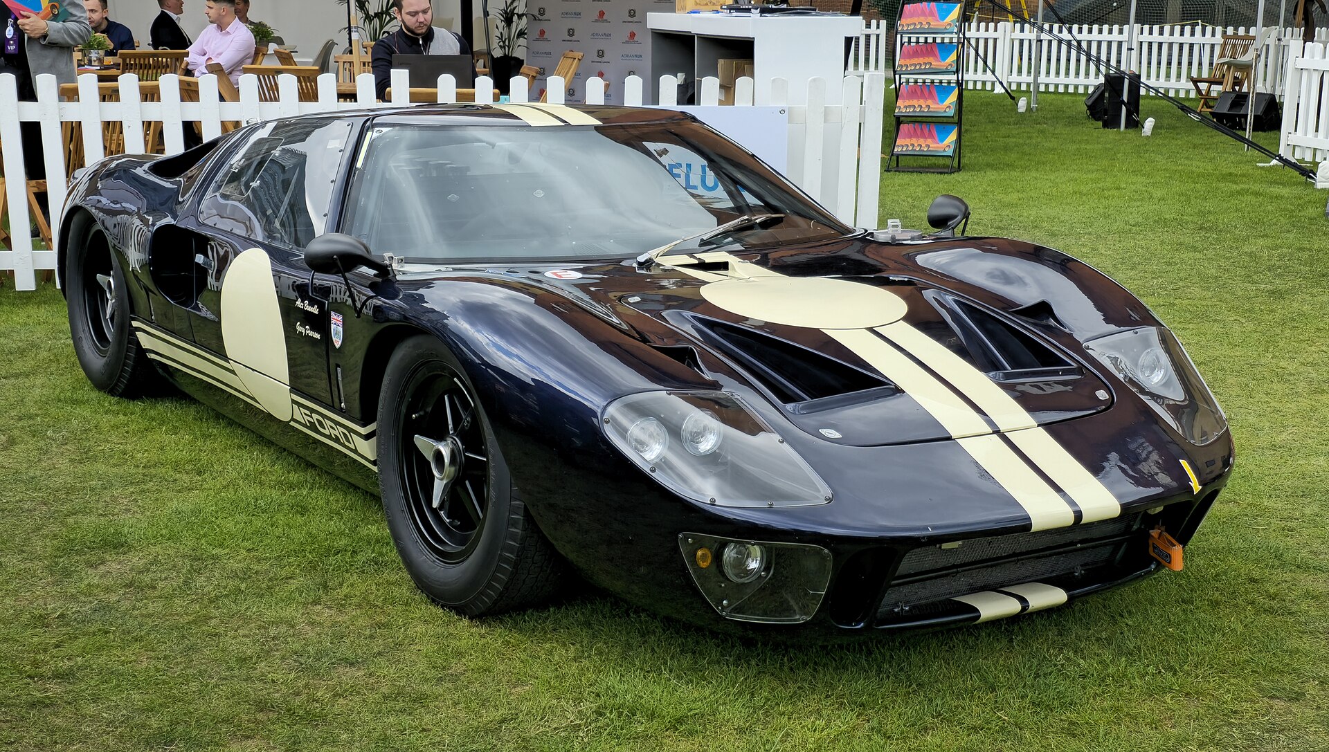 Front three-quarter view of a dark blue Ford GT40 with cream racing stripes