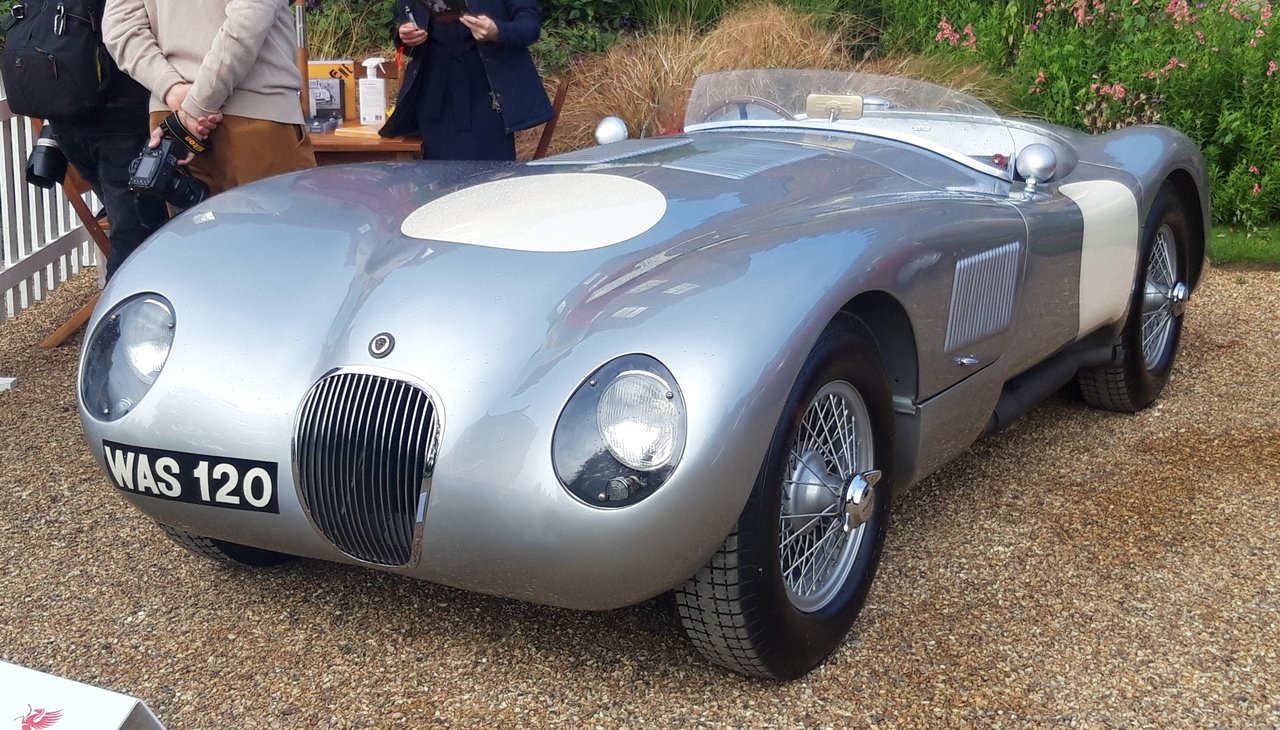 Silver Jaguar C-Type with an open cockpit, wire wheels and white racing roundels
