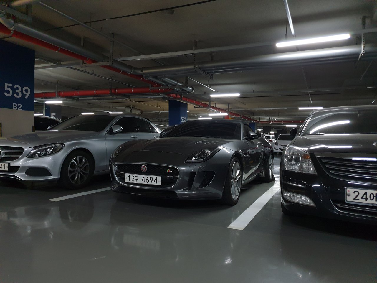 Grey Jaguar F-Type convertible viewed from the front and side in a parking garage