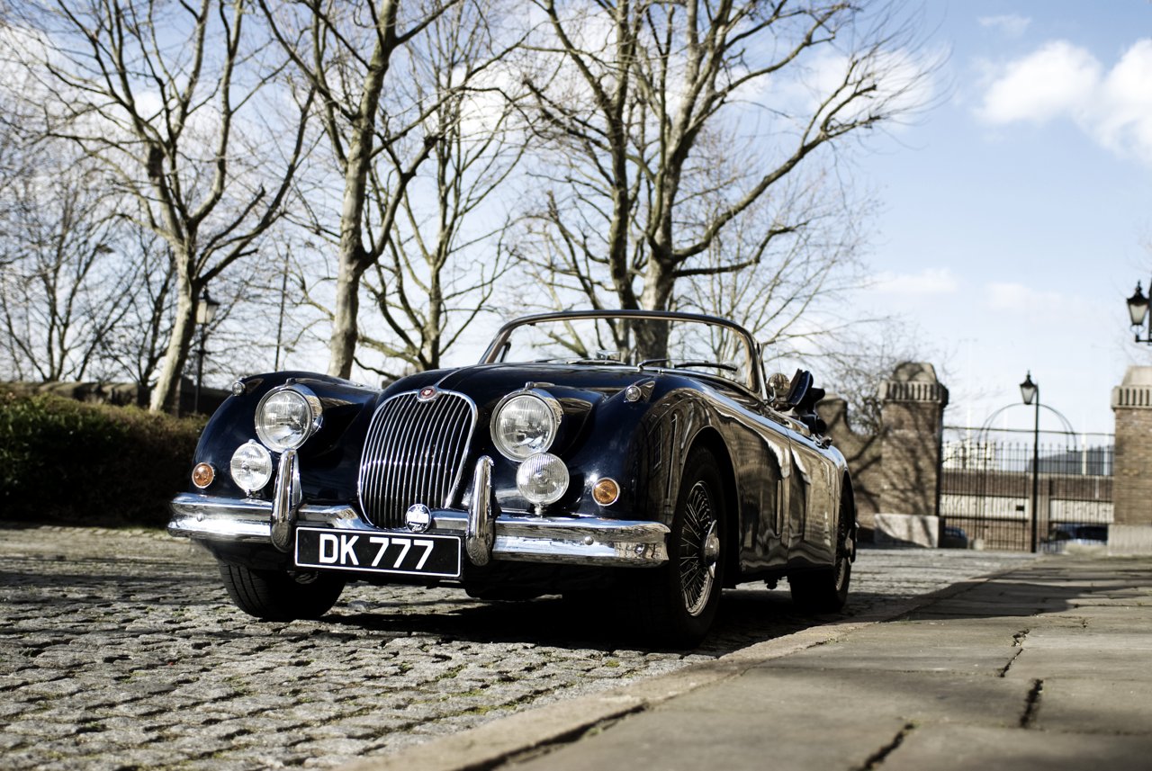 Dark blue Jaguar XK150 drophead coupé with its roof lowered, viewed from the front
