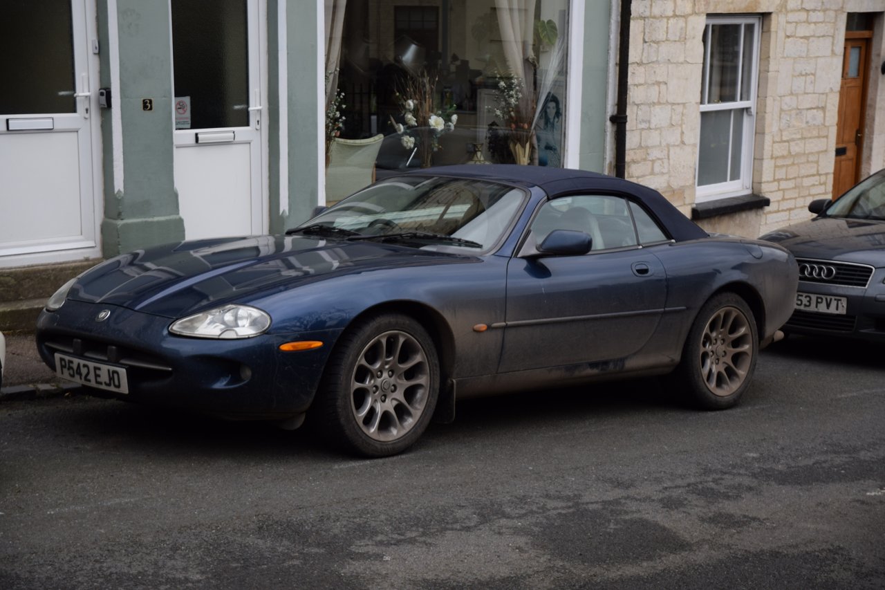 Blue Jaguar XK8 convertible viewed from the front and side with its fabric roof raised