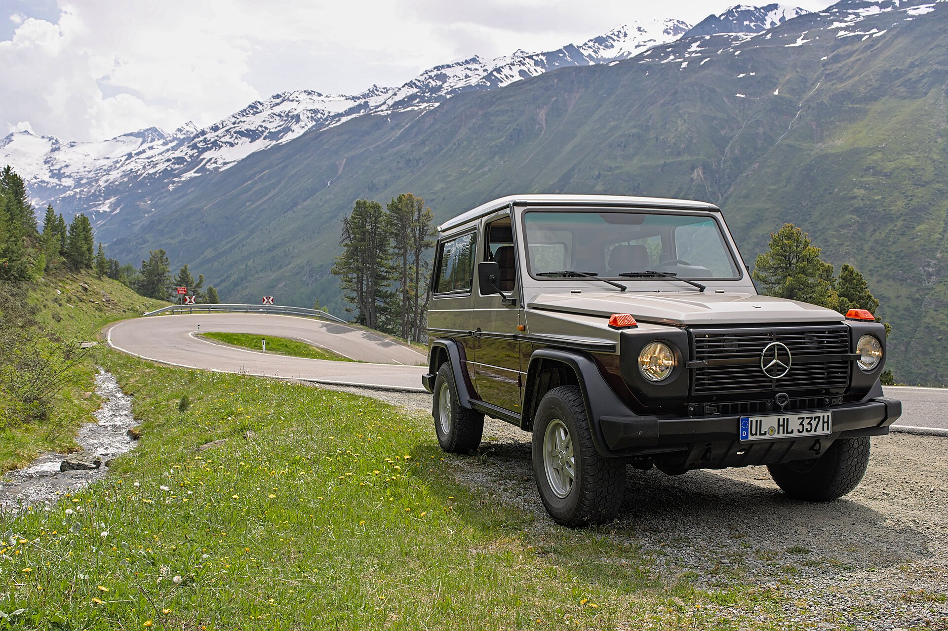 Front three-quarter view of a grey Mercedes-Benz 250 GD W460 on an Alpine road